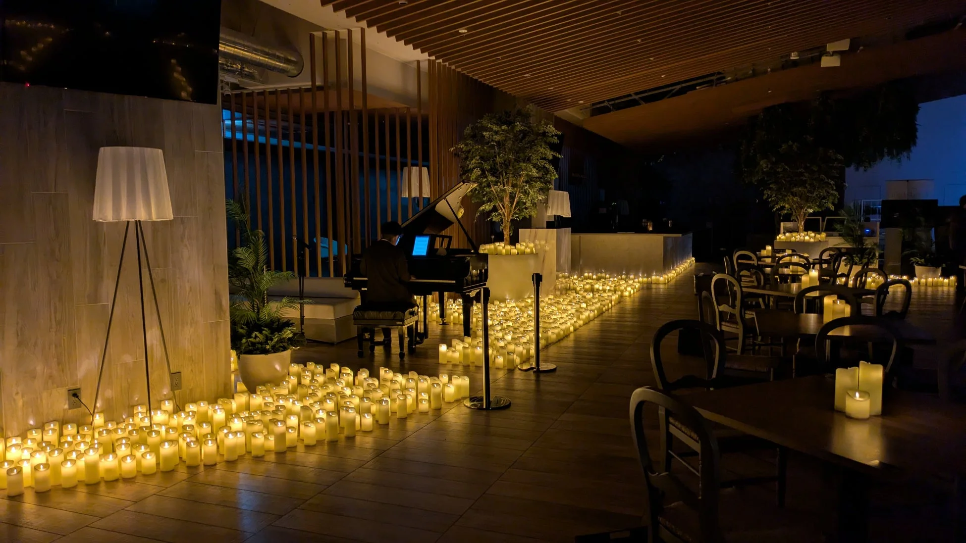 無数のキャンドルが床に並べられ、グランドピアノの生演奏が行われている、ロマンチックで落ち着いた雰囲気の屋内の空間