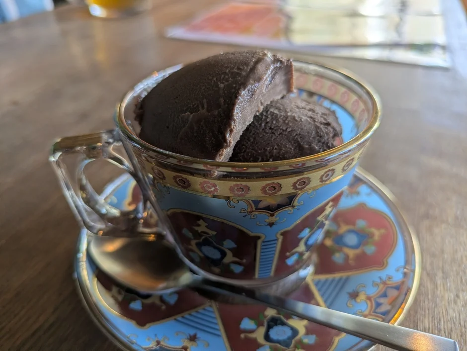 おしゃれなカップに入ったチョコレートアイスクリームの接写です。美しい模様のカップとソーサーがデザートの時間を彩っています。