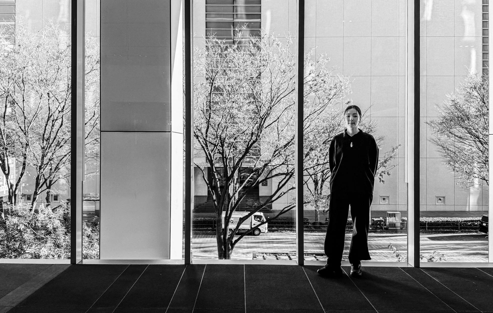 大きな窓の前に立つ女性の白黒写真