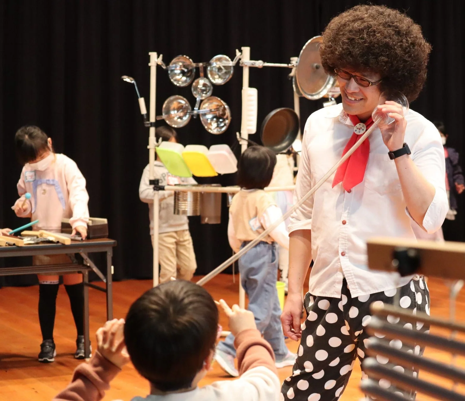 アフロヘアーの男性が子供たちに手作り楽器を使ったワークショップを行う様子