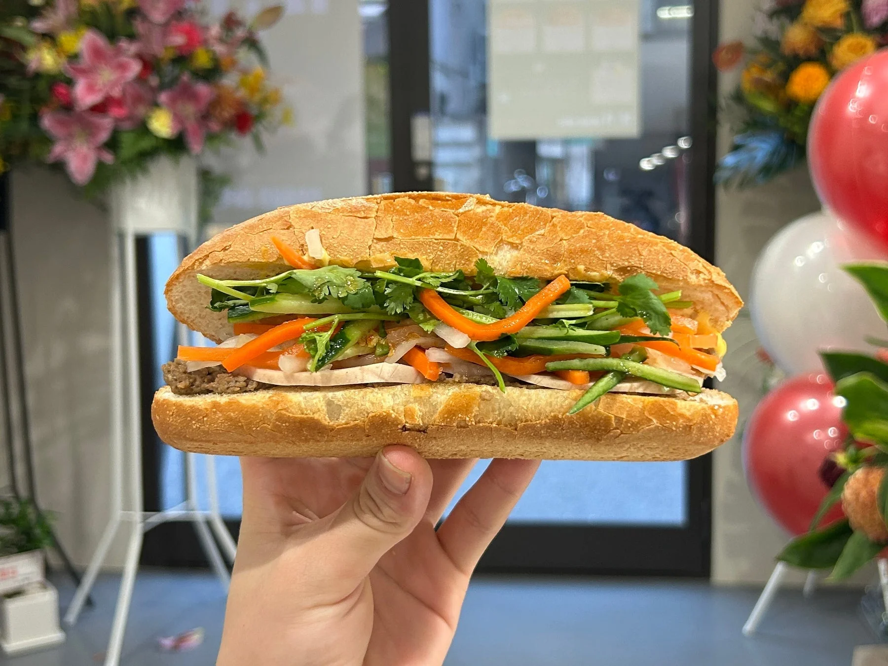 手で持たれた、具材たっぷりのバインミーのクローズアップ写真です。