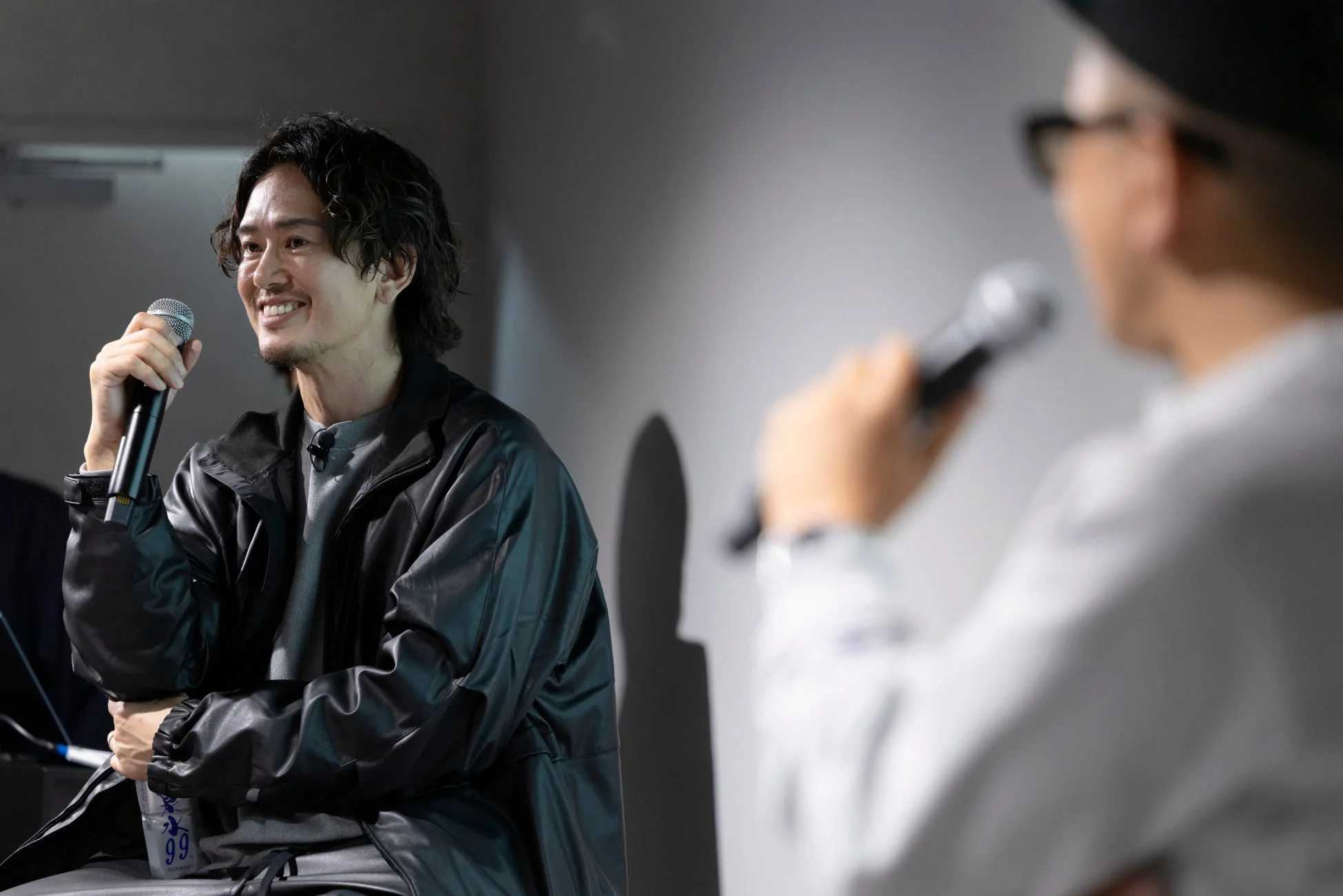 マイクを手に笑顔で話す男性の姿