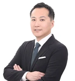 白い背景の前で腕を組んで立つ、スーツ姿のアジア系男性のプロフェッショナルなポートレート写真