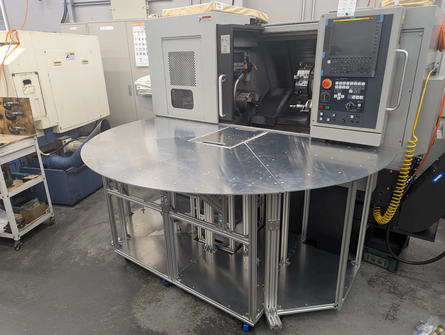 工場の作業場に設置された大型のCNC旋盤が中心の画像です