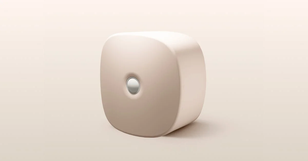 淡いベージュ色の丸みを帯びた長方形の電子機器が、中央に銀色のボタンを配して置かれています。