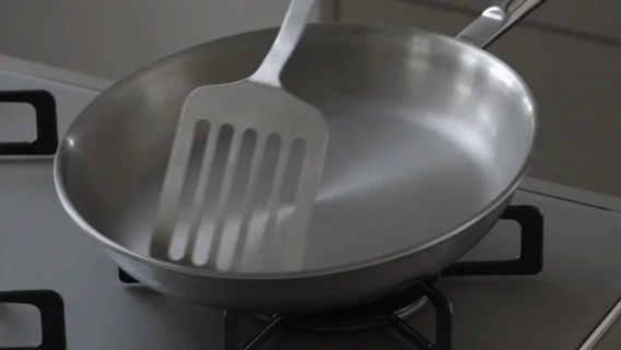 ガスコンロの上のステンレス製フライパンとフライ返し
