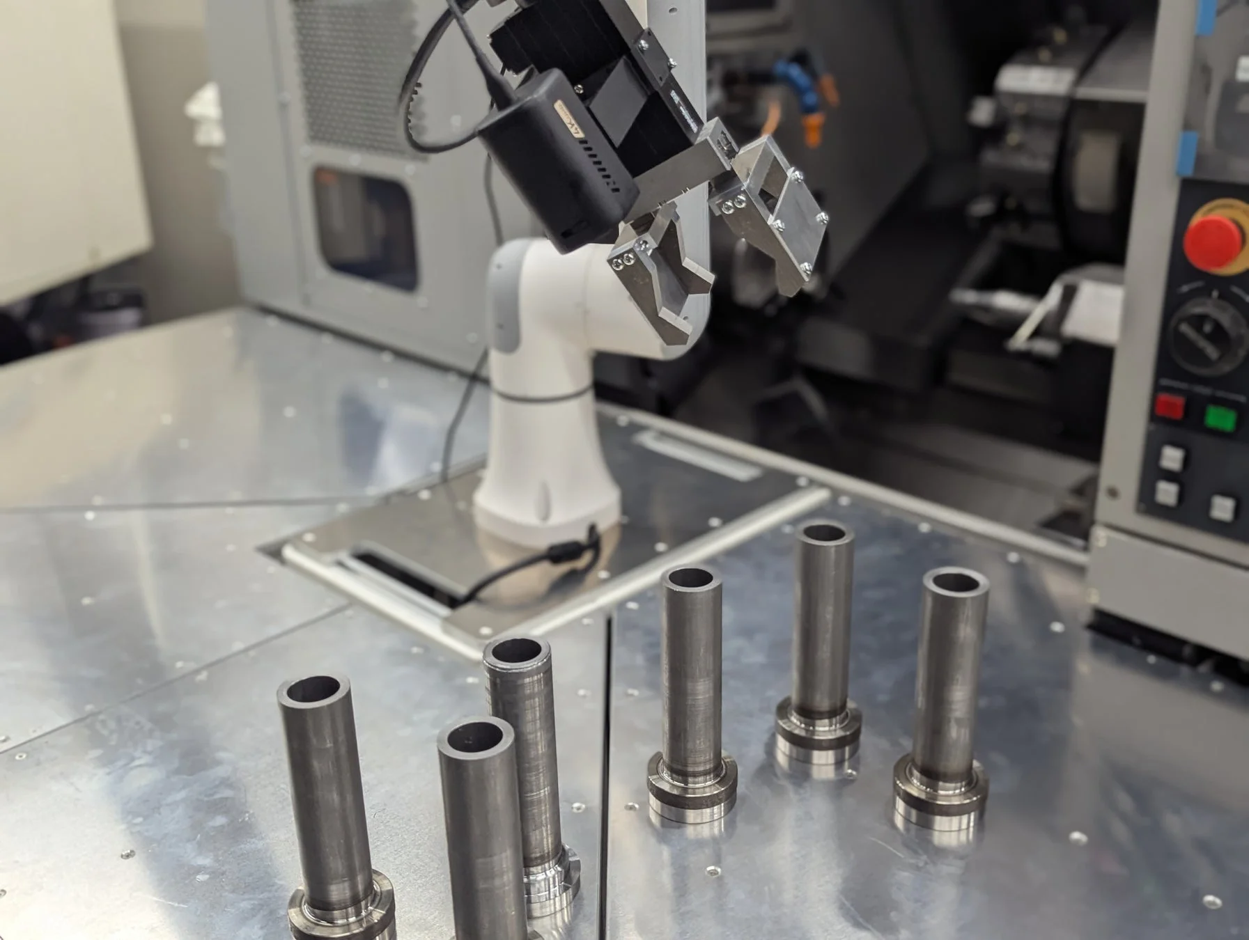 ロボットアームが金属部品の近くに位置しており、産業用オートメーション環境での部品のハンドリングを示唆