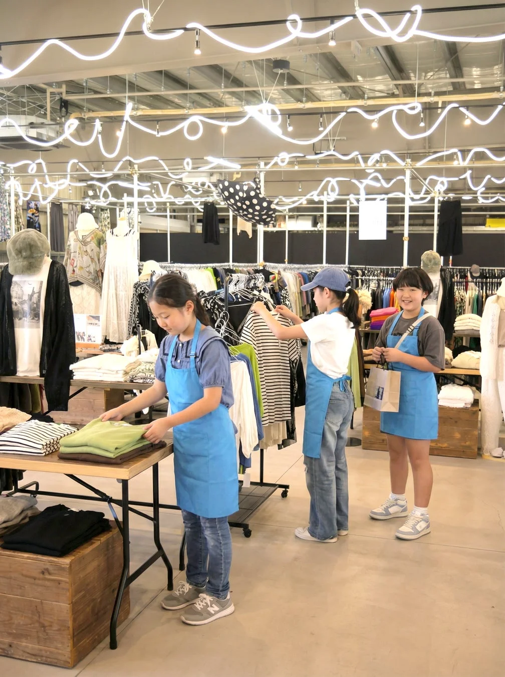青いエプロンを着て商品を陳列する子供たち