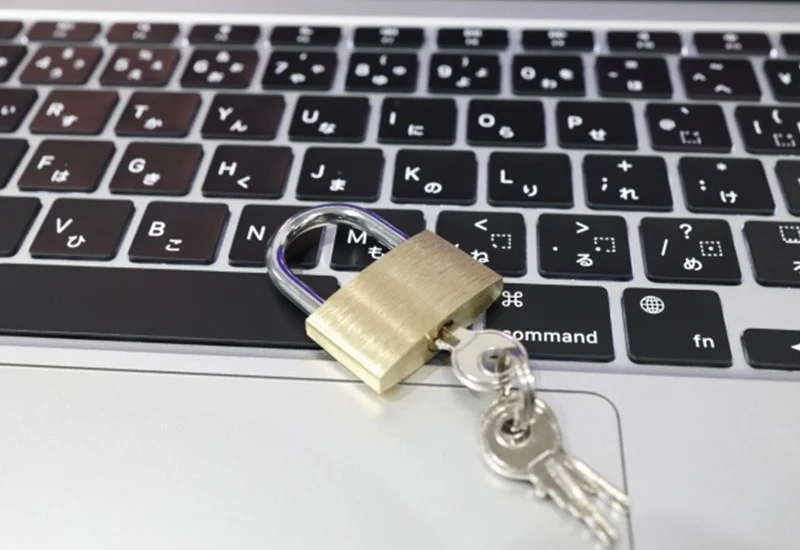ノートパソコンのキーボード上に南京錠と鍵が置かれている