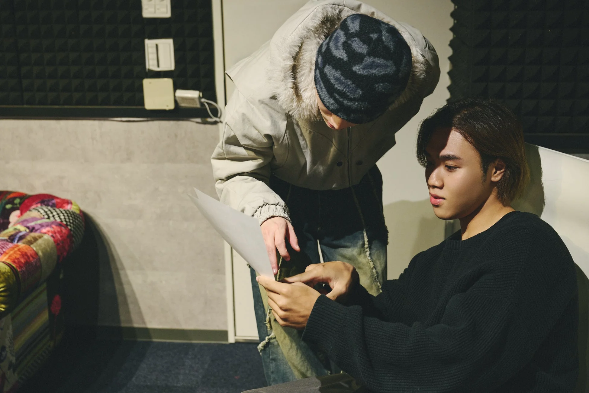 スタジオで書類を囲んで打ち合わせをする若い男性二人