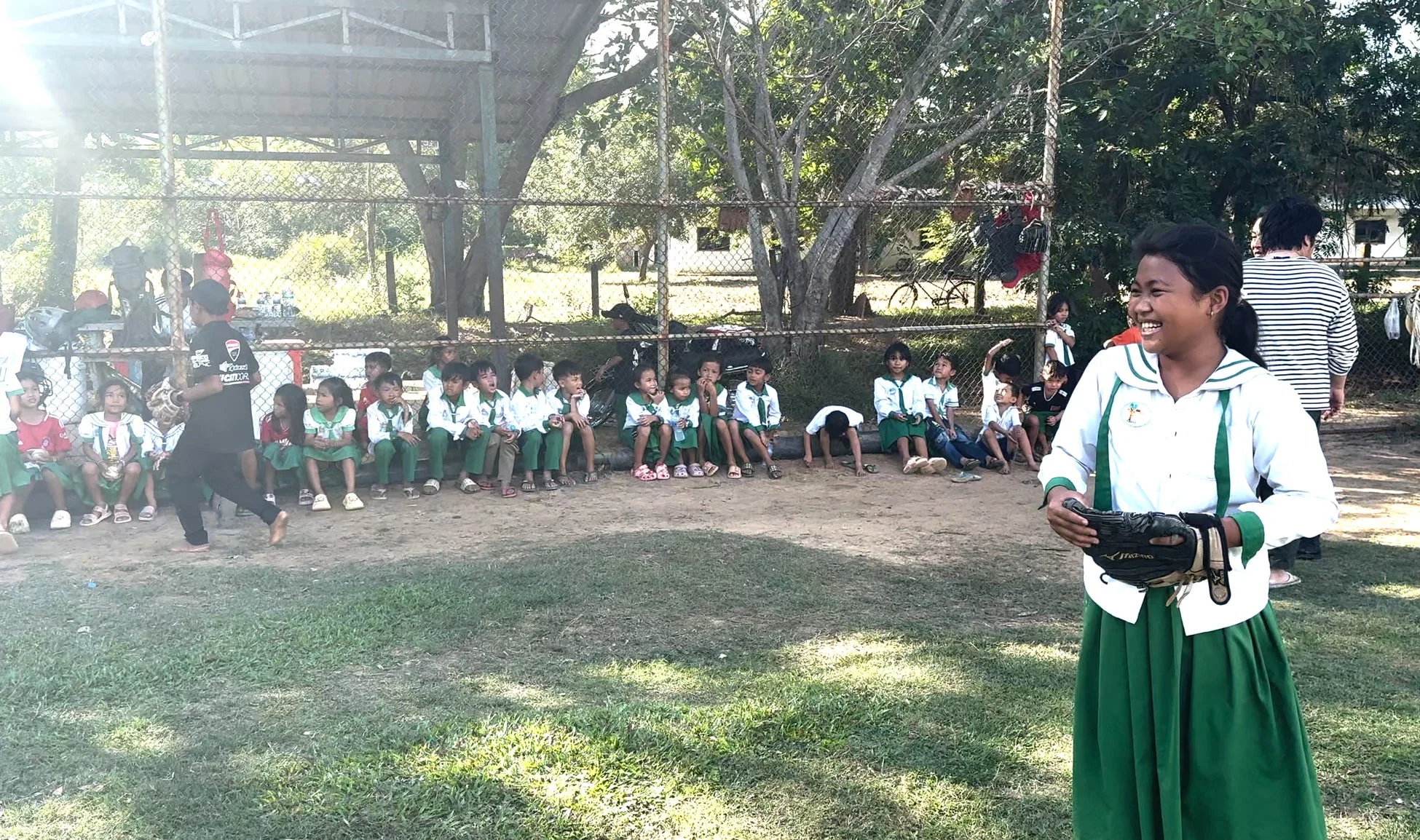 野球グローブを持つ笑顔の少女と多くの子供たち
