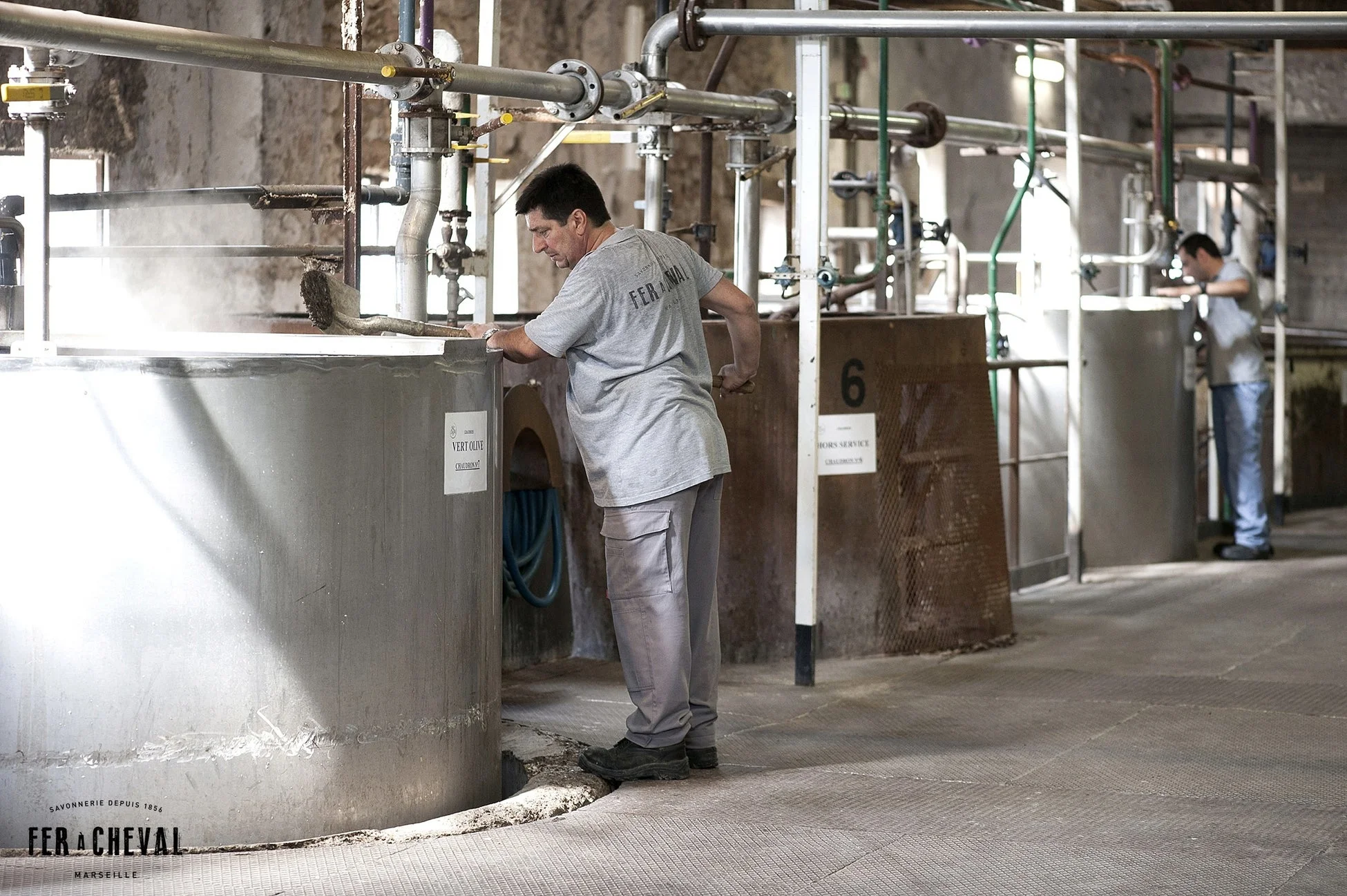 伝統的な石鹸工場で釜をかき混ぜる男性