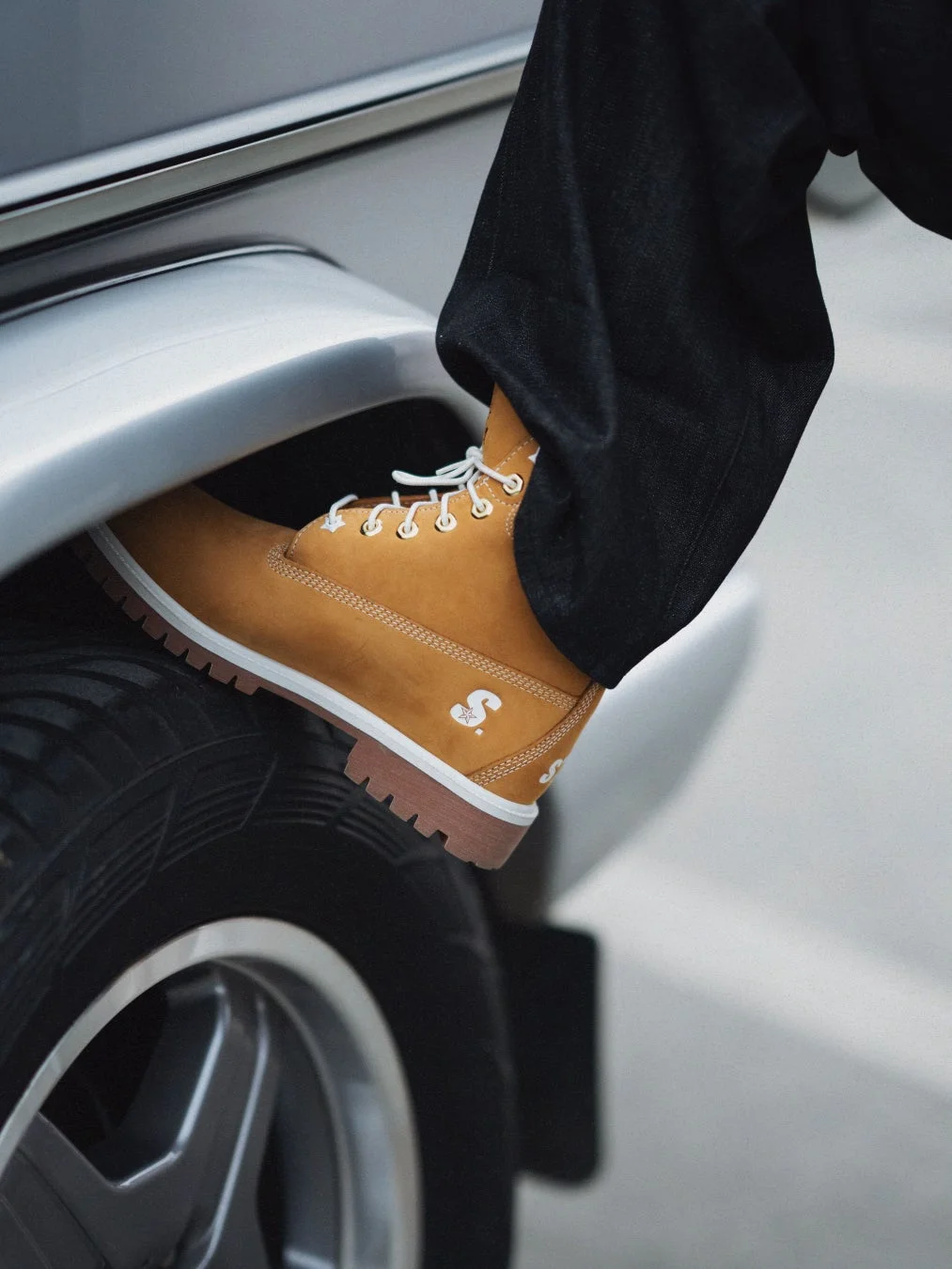 黄色のワークブーツと黒いジーンズを着用した足