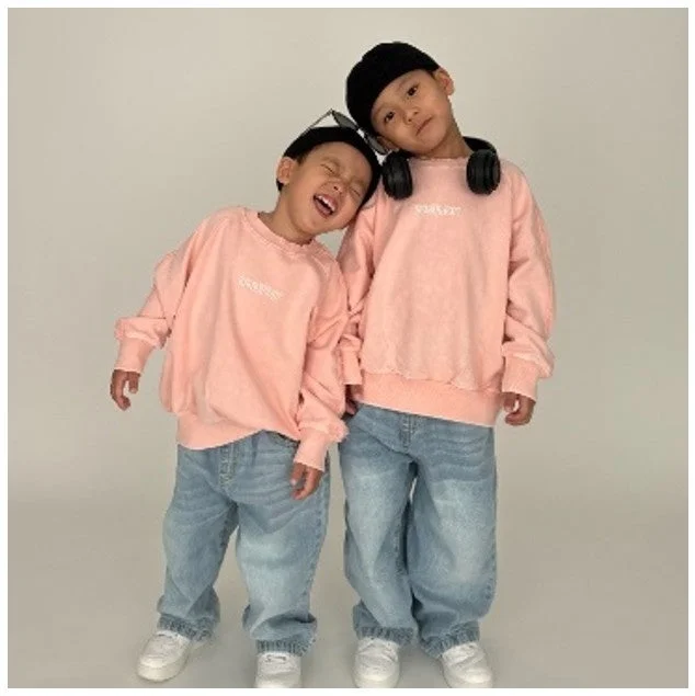 お揃いのピンクスウェットとデニムを着用した二人の男の子