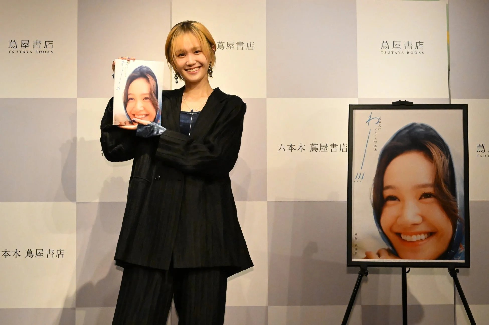 笑顔で写真集を持つ尾碕真花