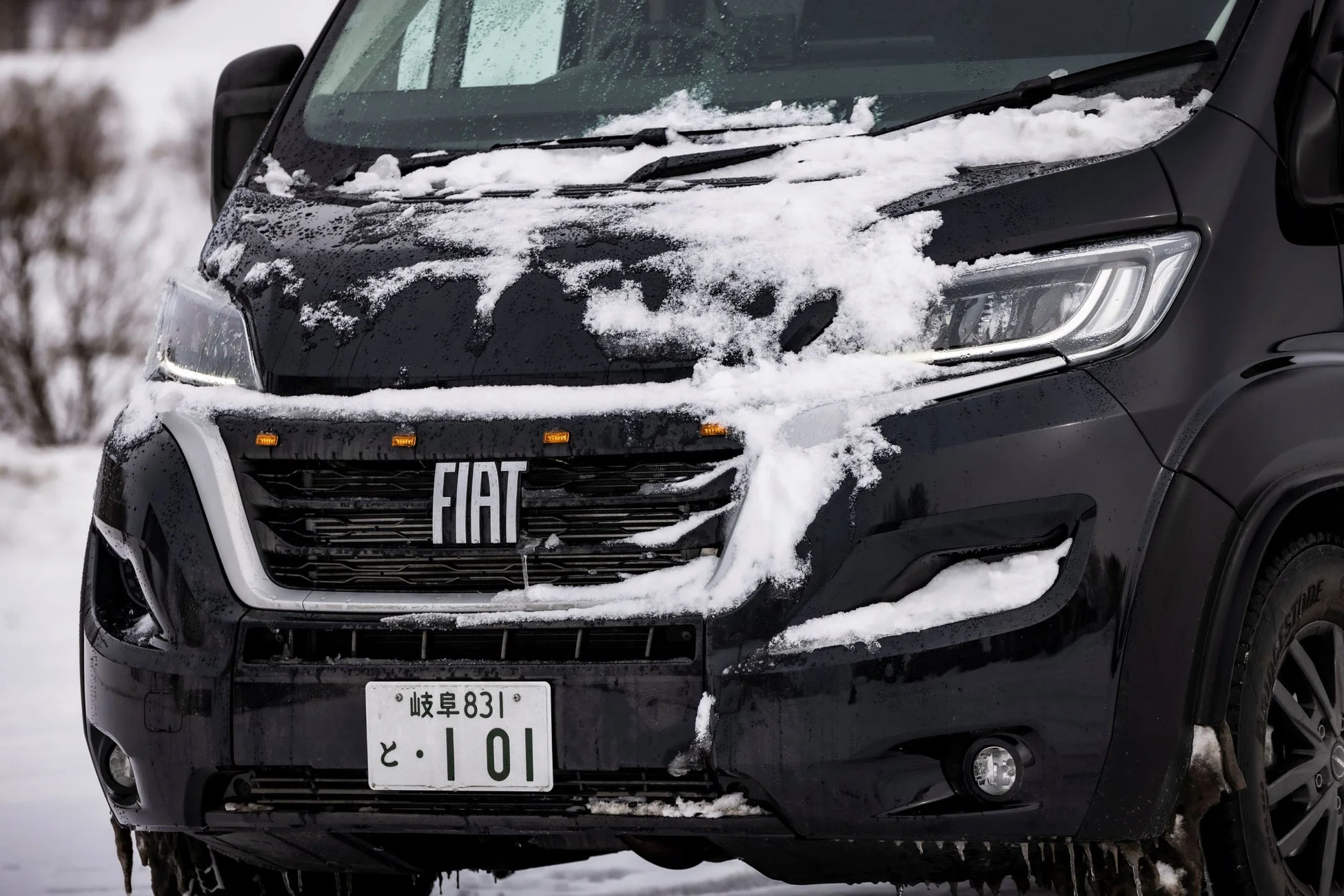 雪が積もった黒いフィアットのバン