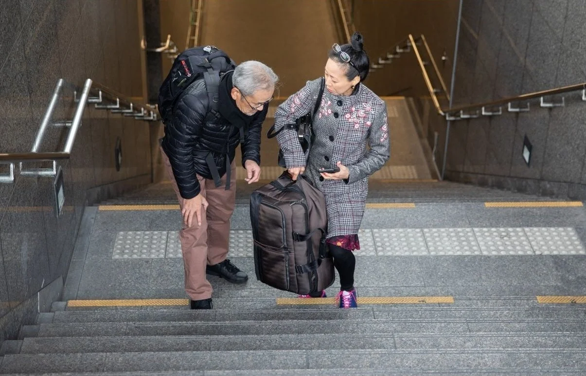 階段で荷物を運ぶ高齢者