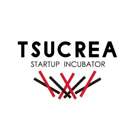 「TSUCREA STARTUP INCUBATOR」という文字と、赤と黒の線が交差する抽象的なデザインが特徴的なロゴマークです。白背景に黒い文字と対照的な色の線が配置されています。