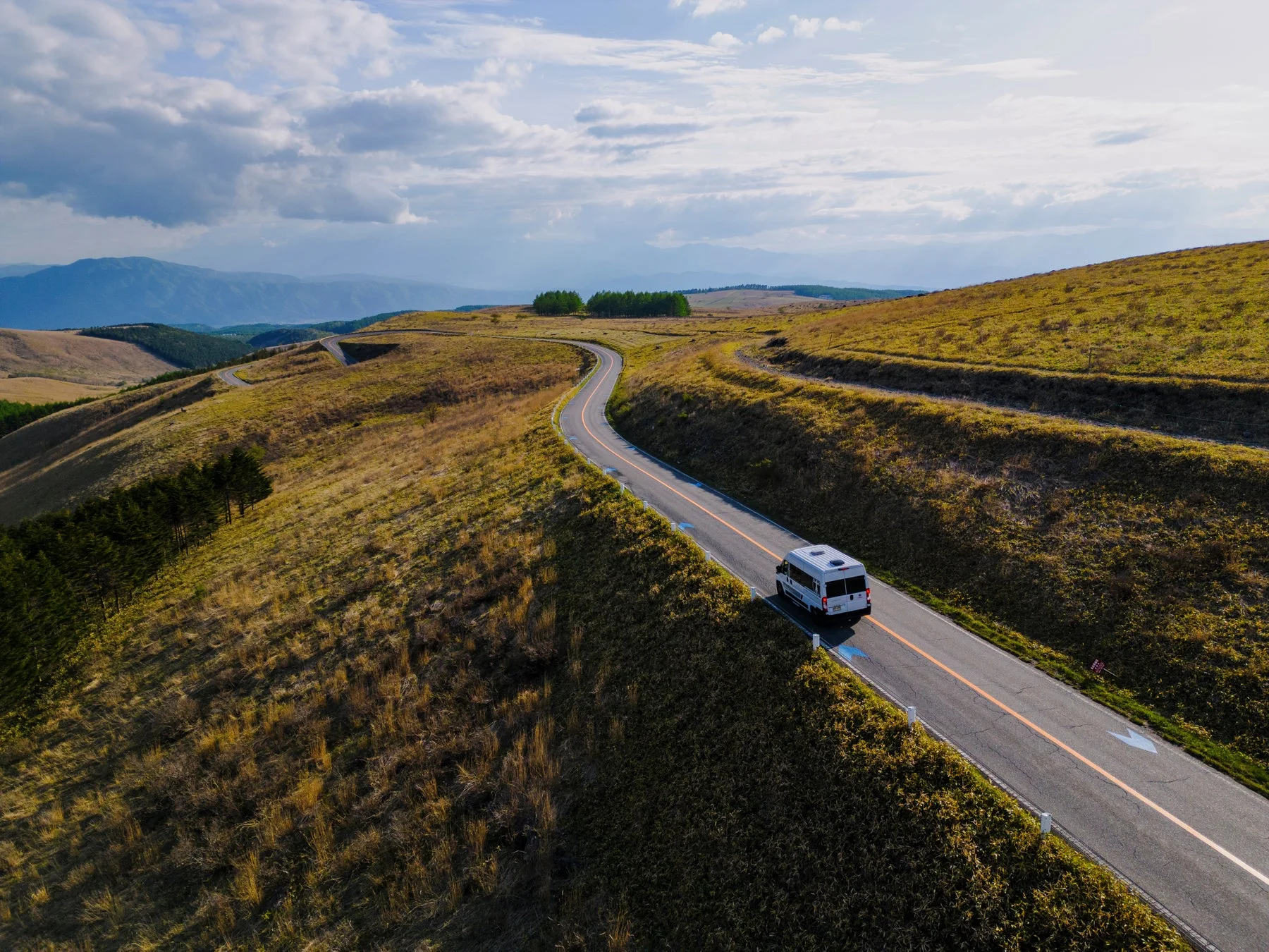 丘陵地帯を走る白いキャンピングカー