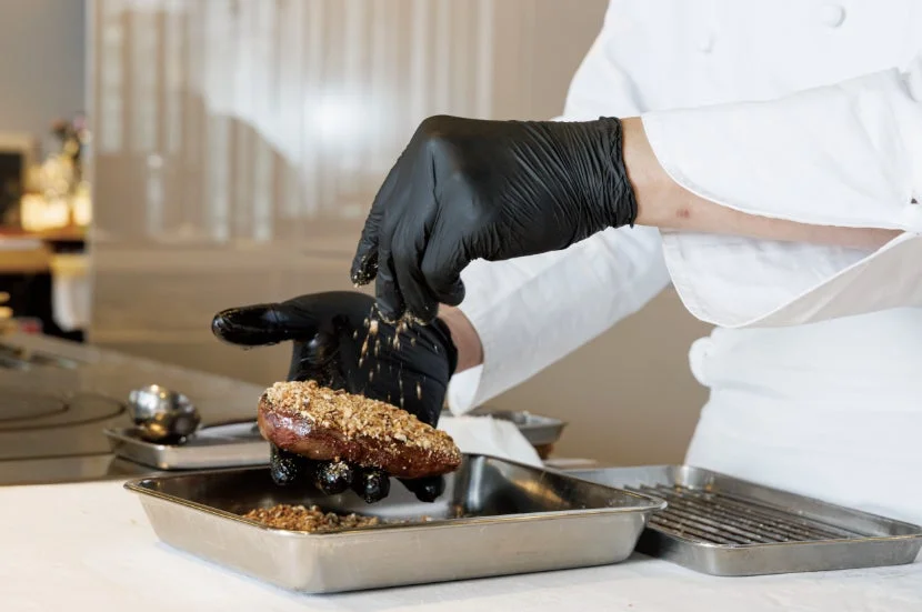 肉にトッピングを施すシェフの手