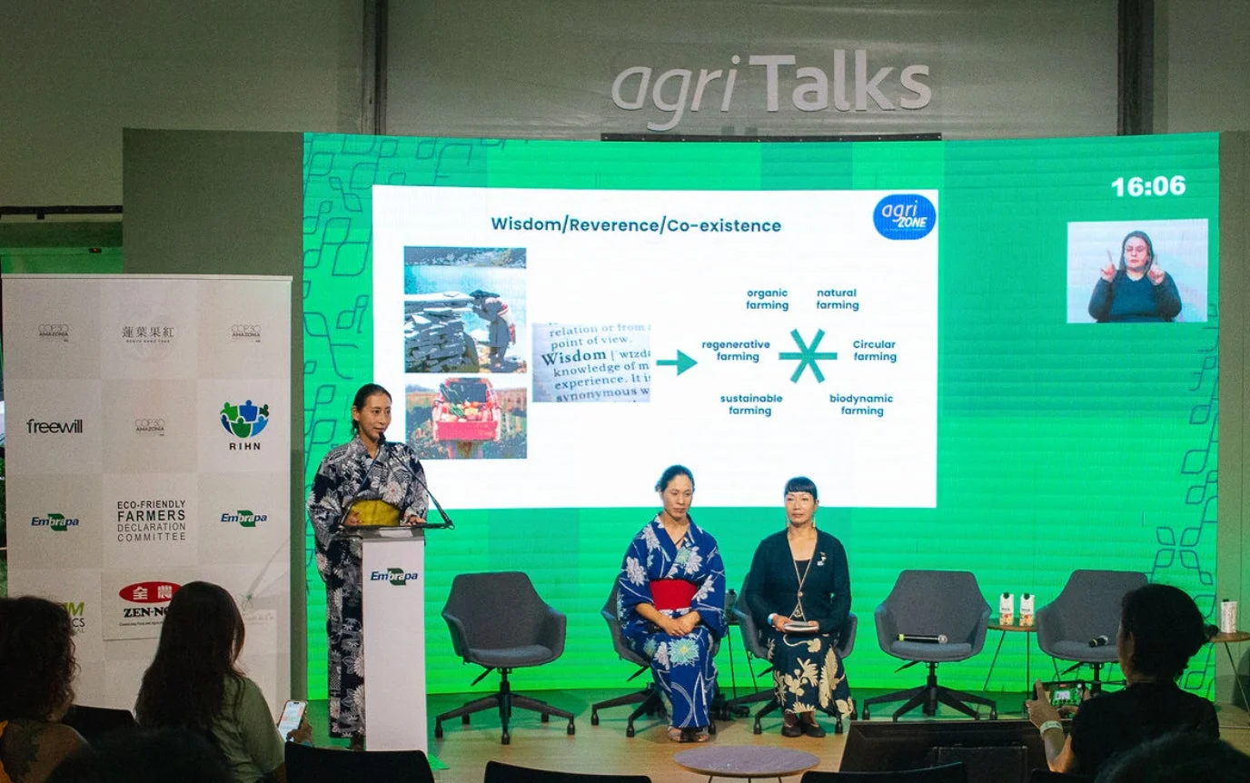 日本の伝統衣装を着た人々が登壇し、持続可能な農業や共存について語る会議の様子