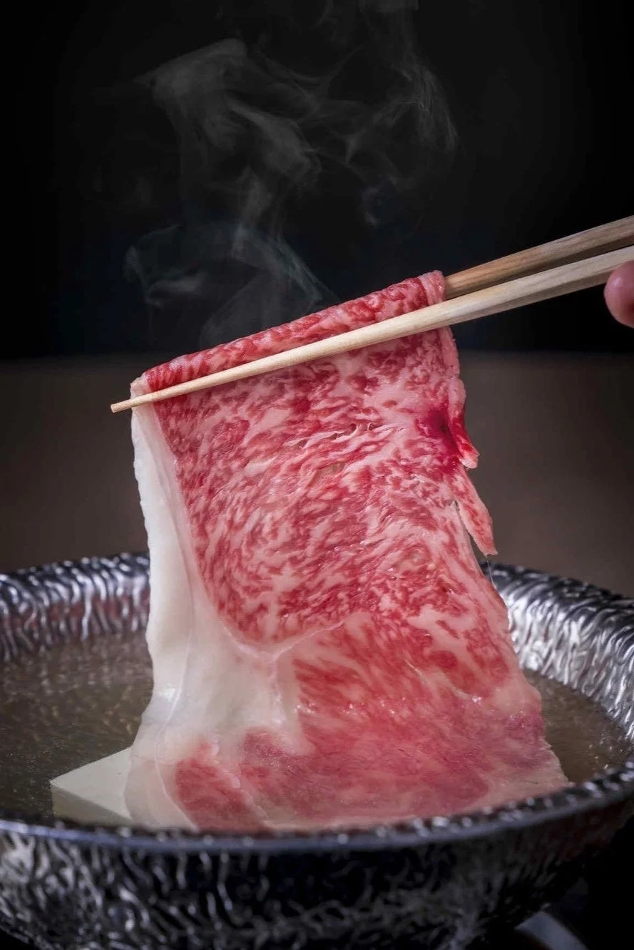 湯気の立つ鍋に浸される霜降りの和牛