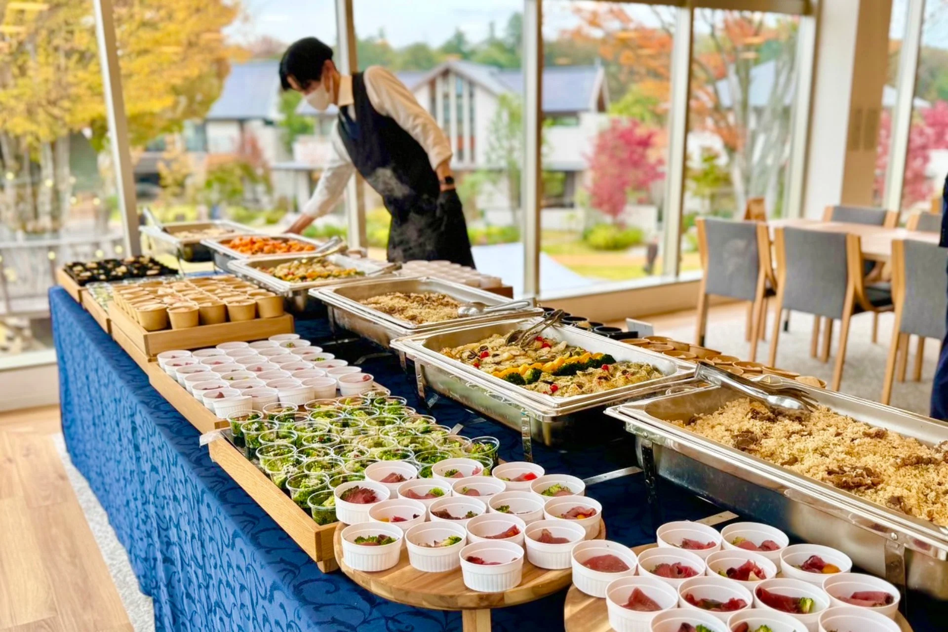 屋内会場でビュッフェ形式の食事が提供され、スタッフが対応している様子