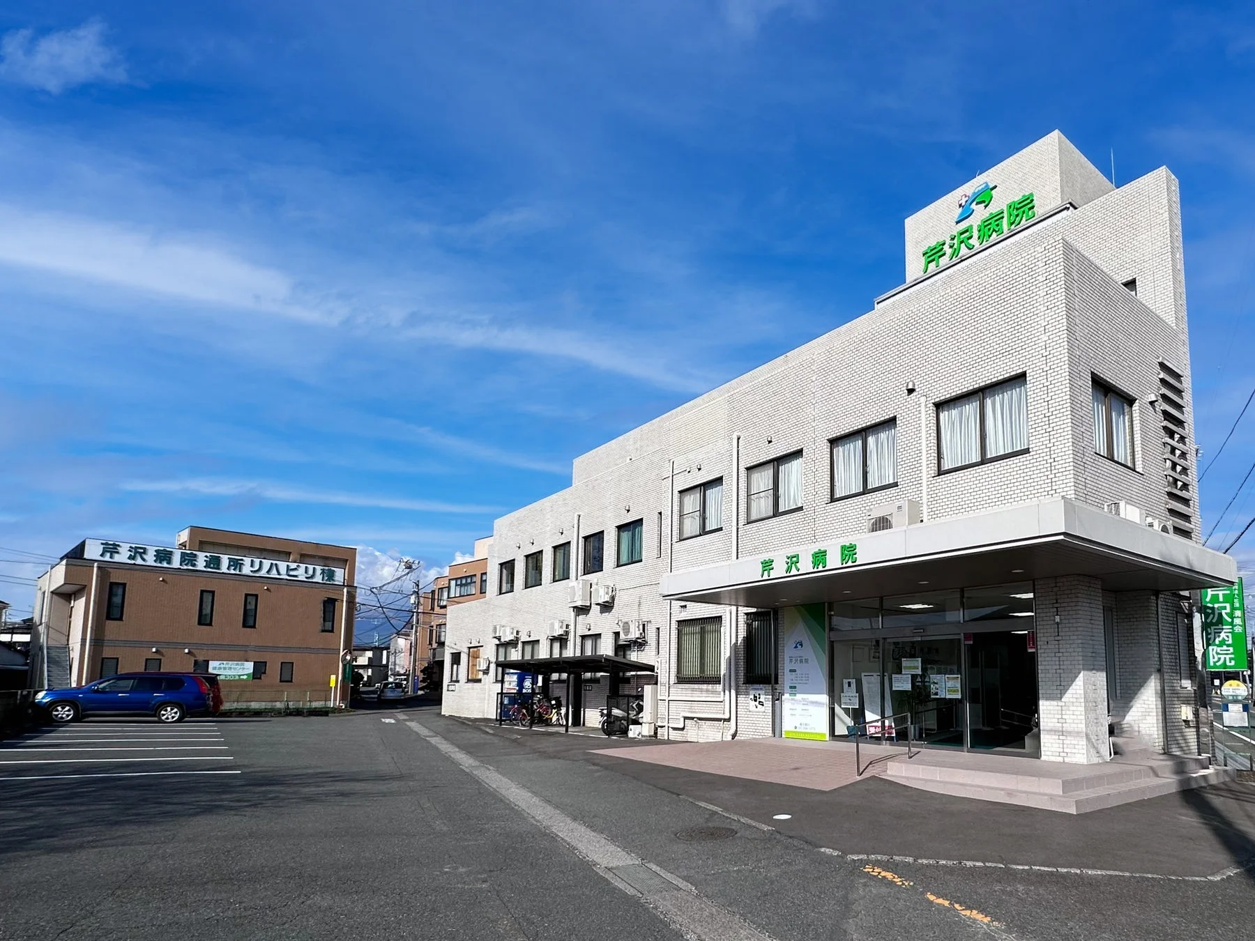 青空の下、芦沢病院の建物が写っている