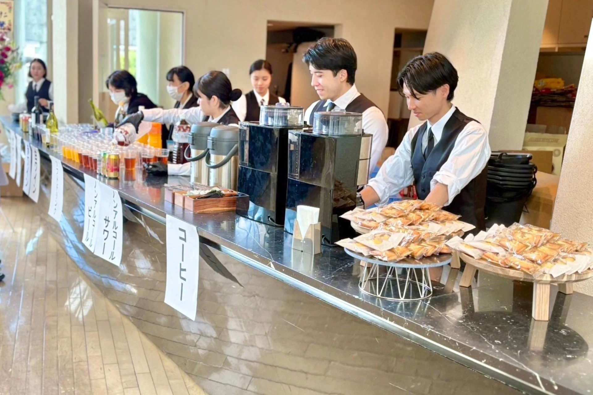 イベント会場でドリンクバーと軽食を提供しているスタッフ