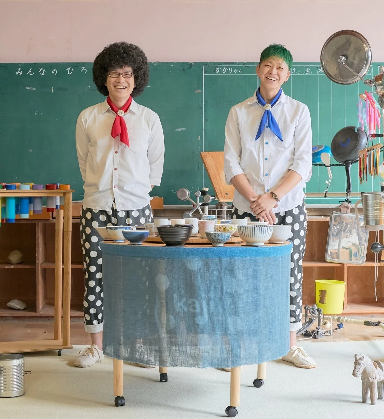 笑顔で立つkajiiの二人と並べられた陶器