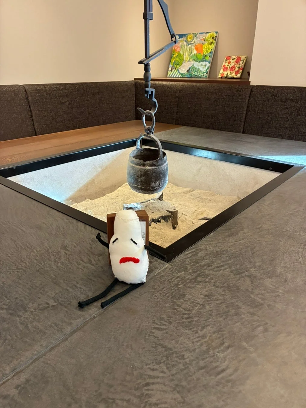 囲炉裏のある部屋に置かれたぬいぐるみ