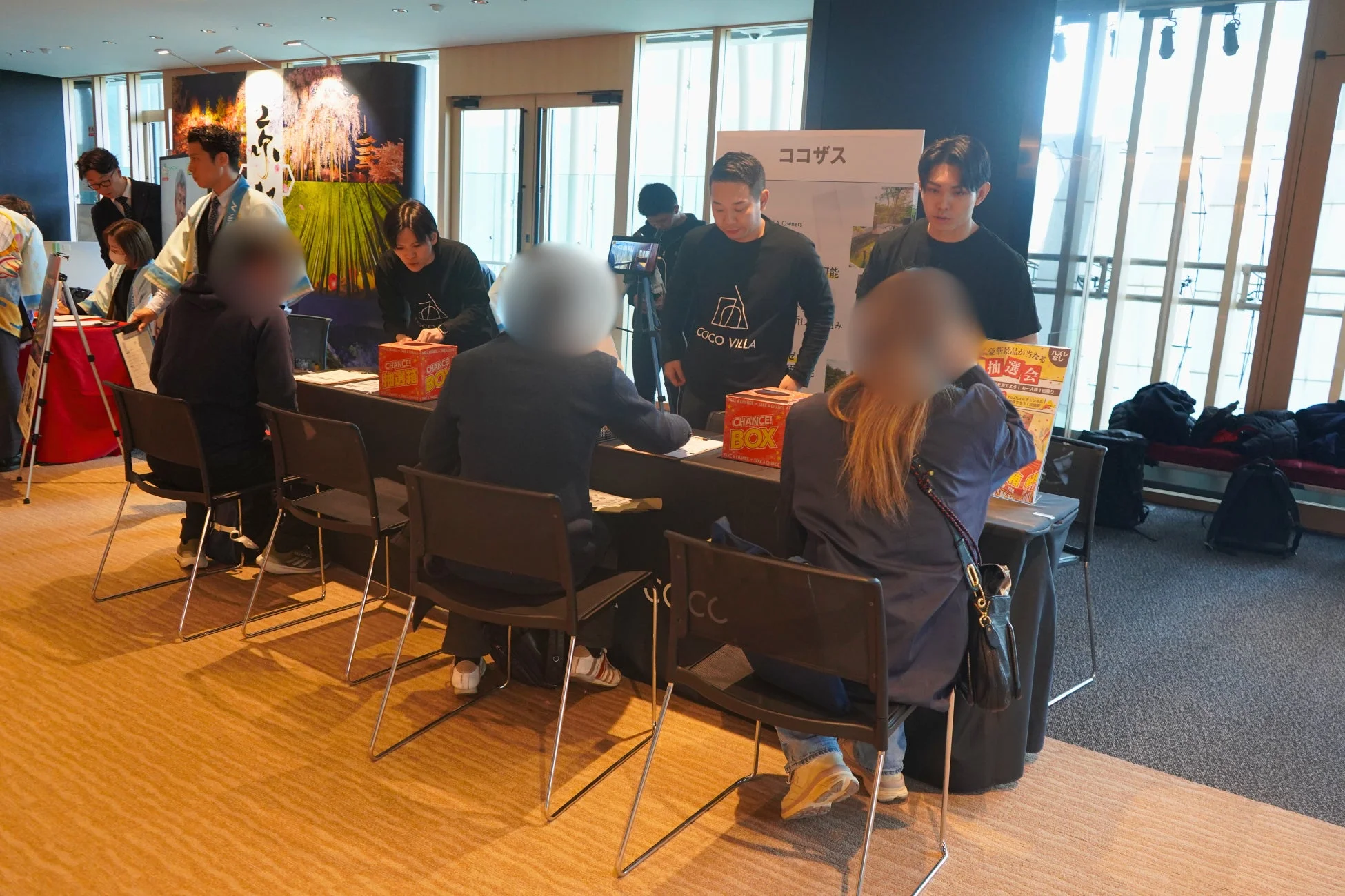イベント会場のブースで、スタッフが来場者に対応し、抽選会が行われている様子