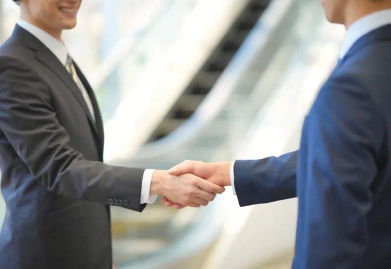 ビジネススーツを着た二人の男性が握手をしている