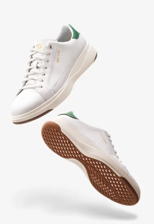 白い背景に、白い革製スニーカーが2足、緑色のヒールタブと茶色のソールを見せて浮遊している製品写真です。モダンでクリーンな印象を与えます。