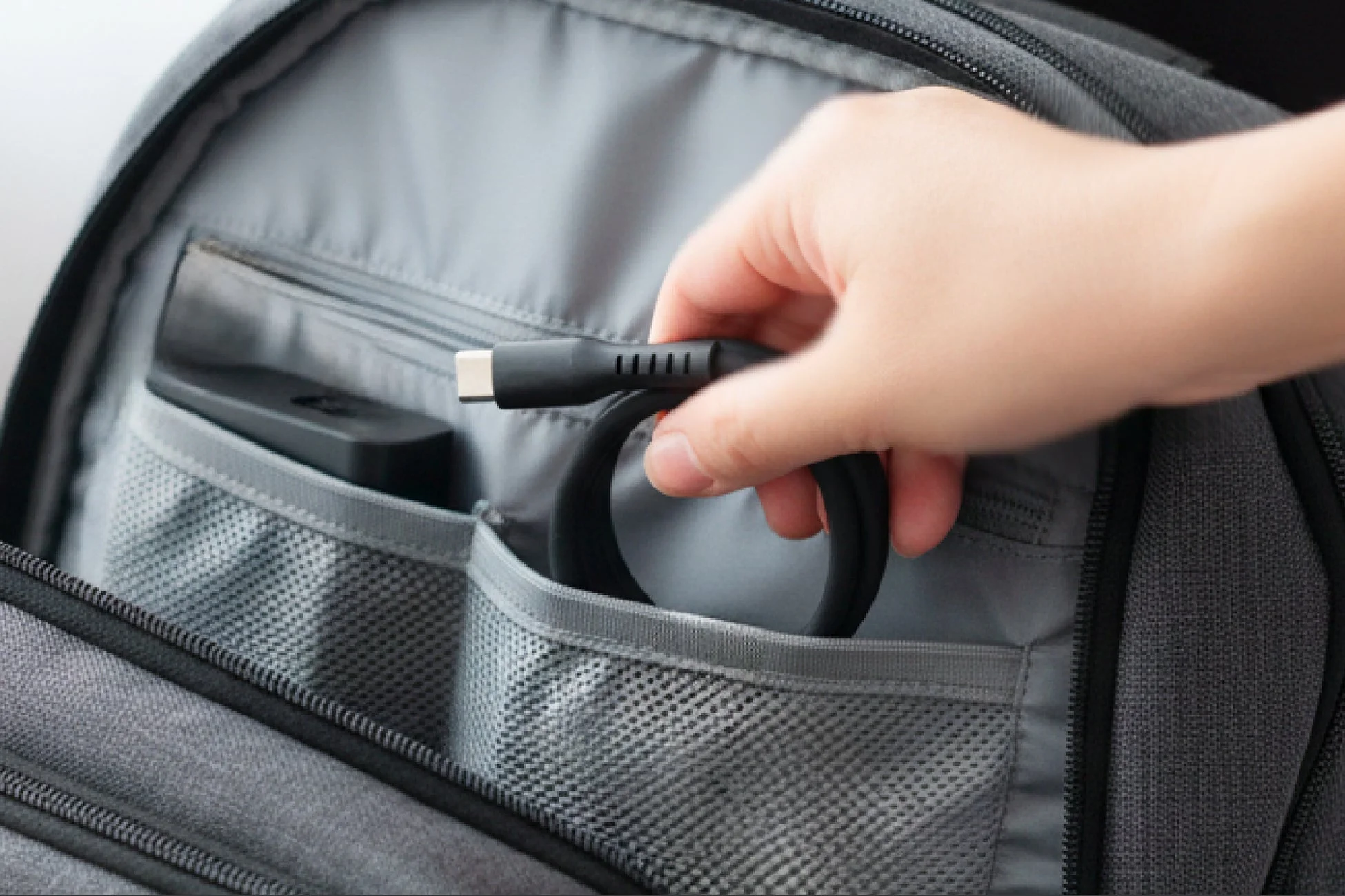 リュックからケーブルを取り出す手