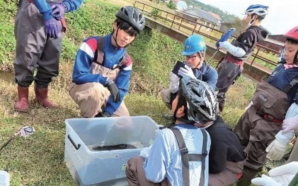 川辺で環境学習をする学生たち