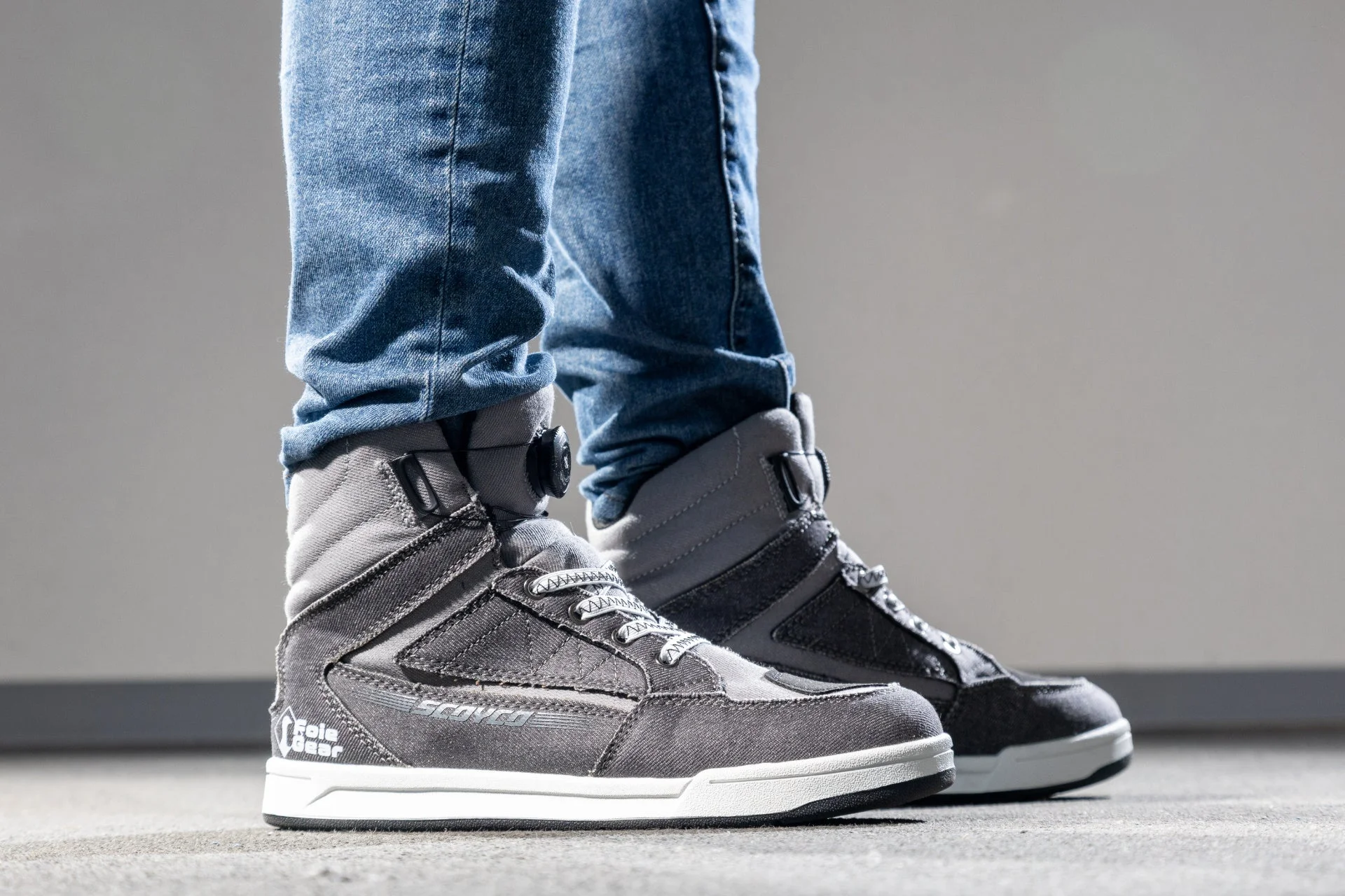 ジーンズを着用した人物が、グレーのハイカットシューズを履いている様子。