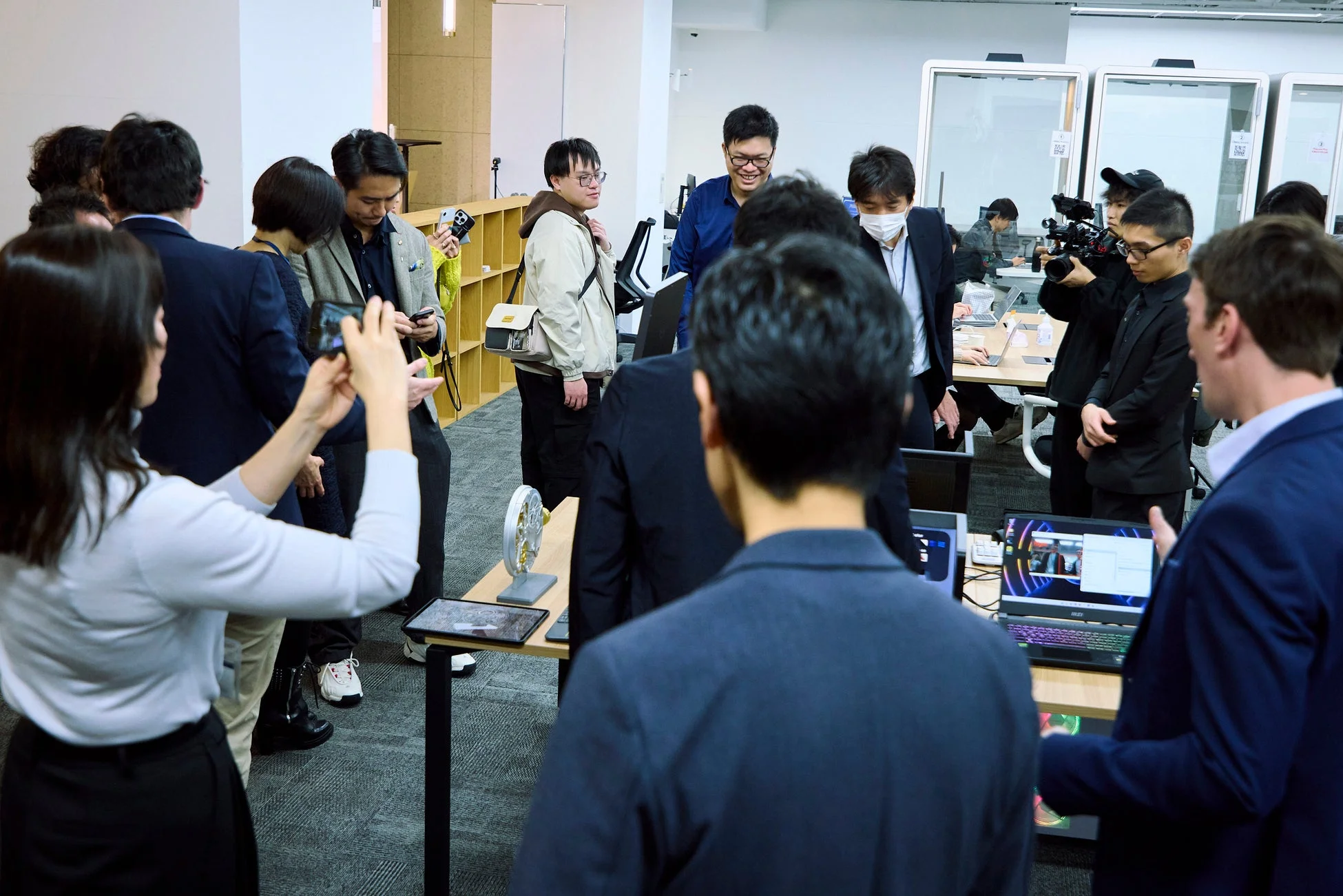 オフィスのような空間で、多くの人々がテクノロジー関連のイベントに参加しています