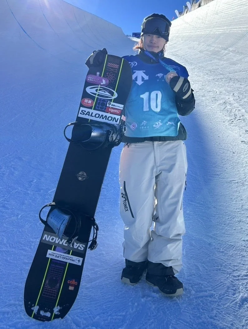 スノーボードとメダルを手に誇らしげに立つ山田琉聖選手