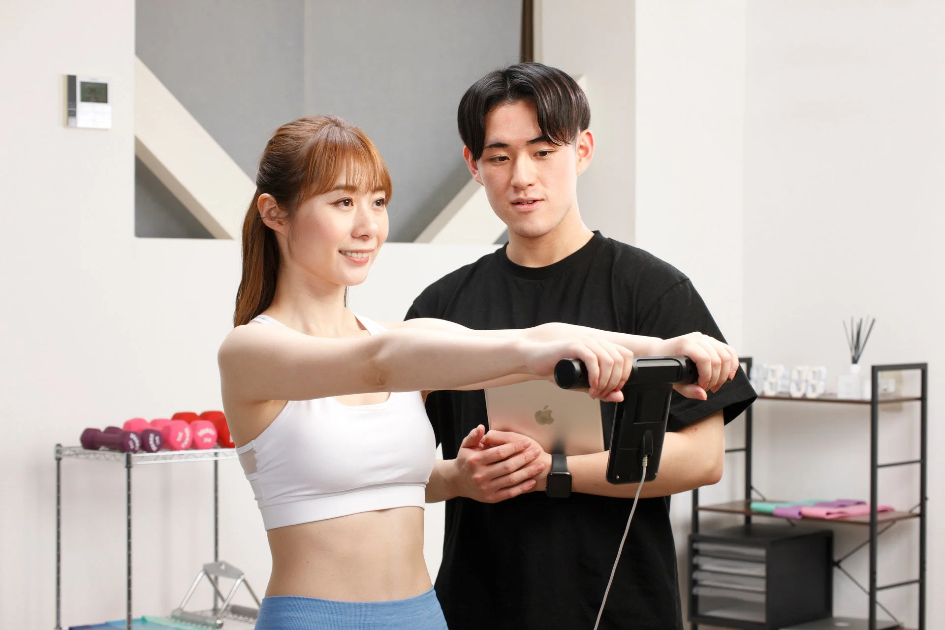 体組成計で測定中の女性とトレーナー