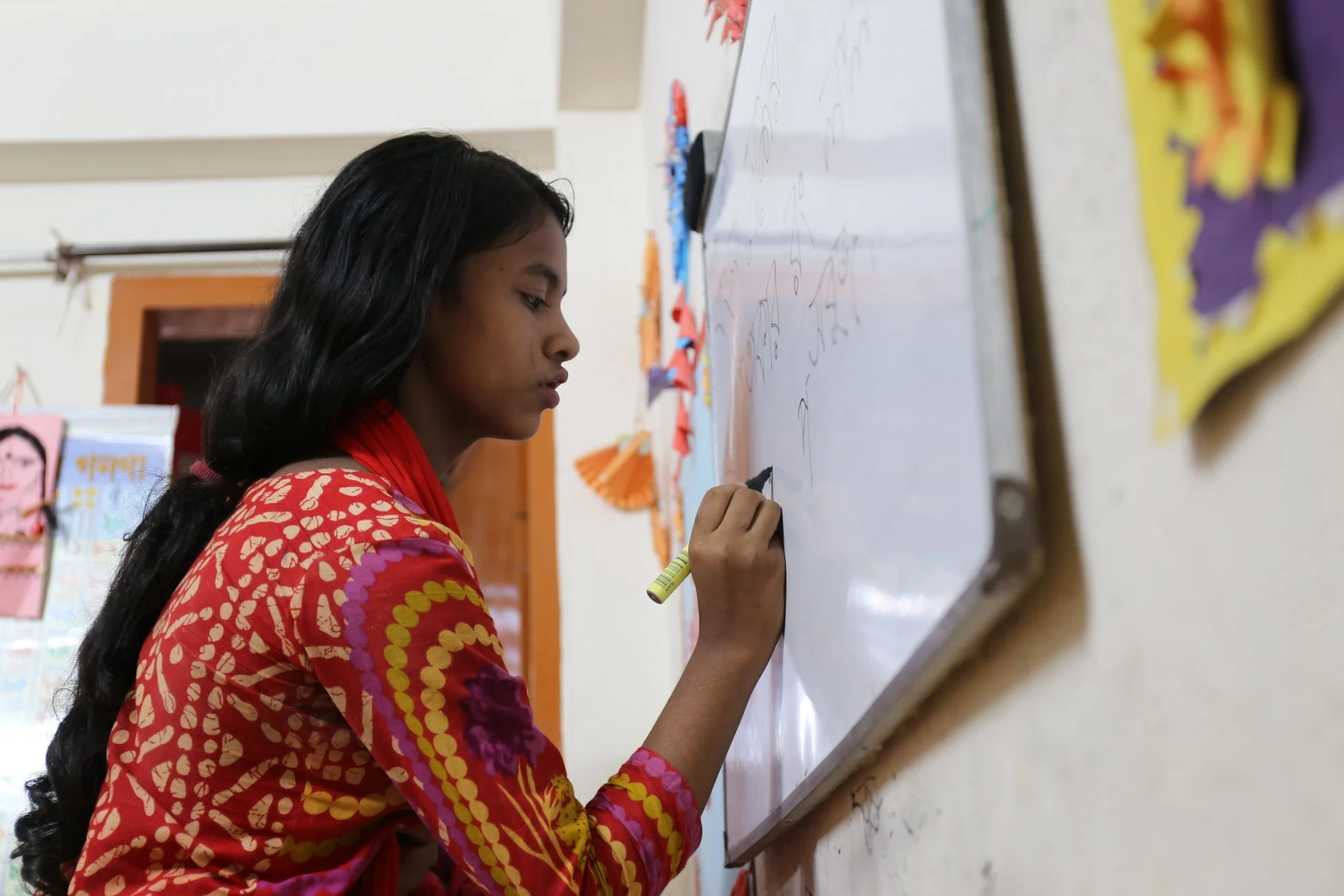 ホワイトボードにベンガル語を書きながら学ぶ少女