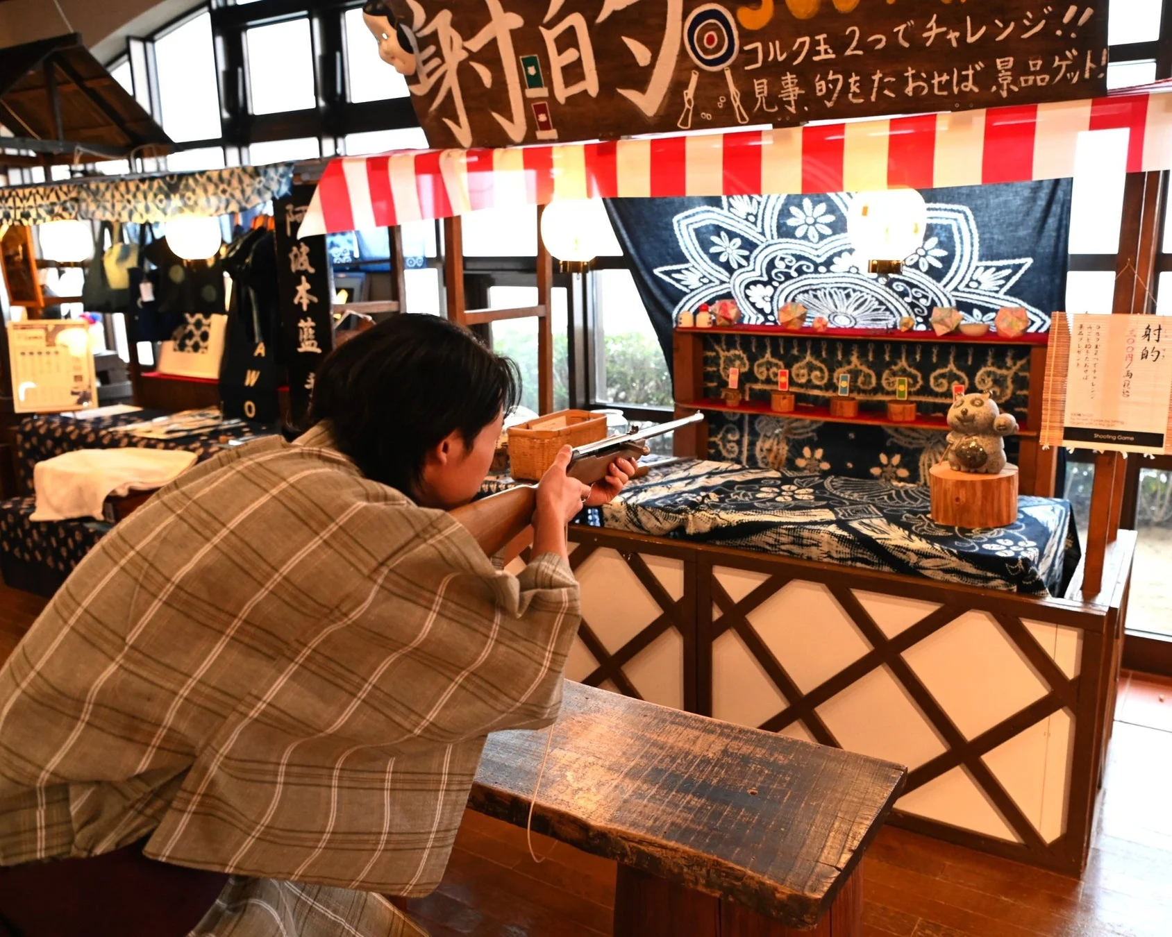 屋内の射的場で的を狙う人物