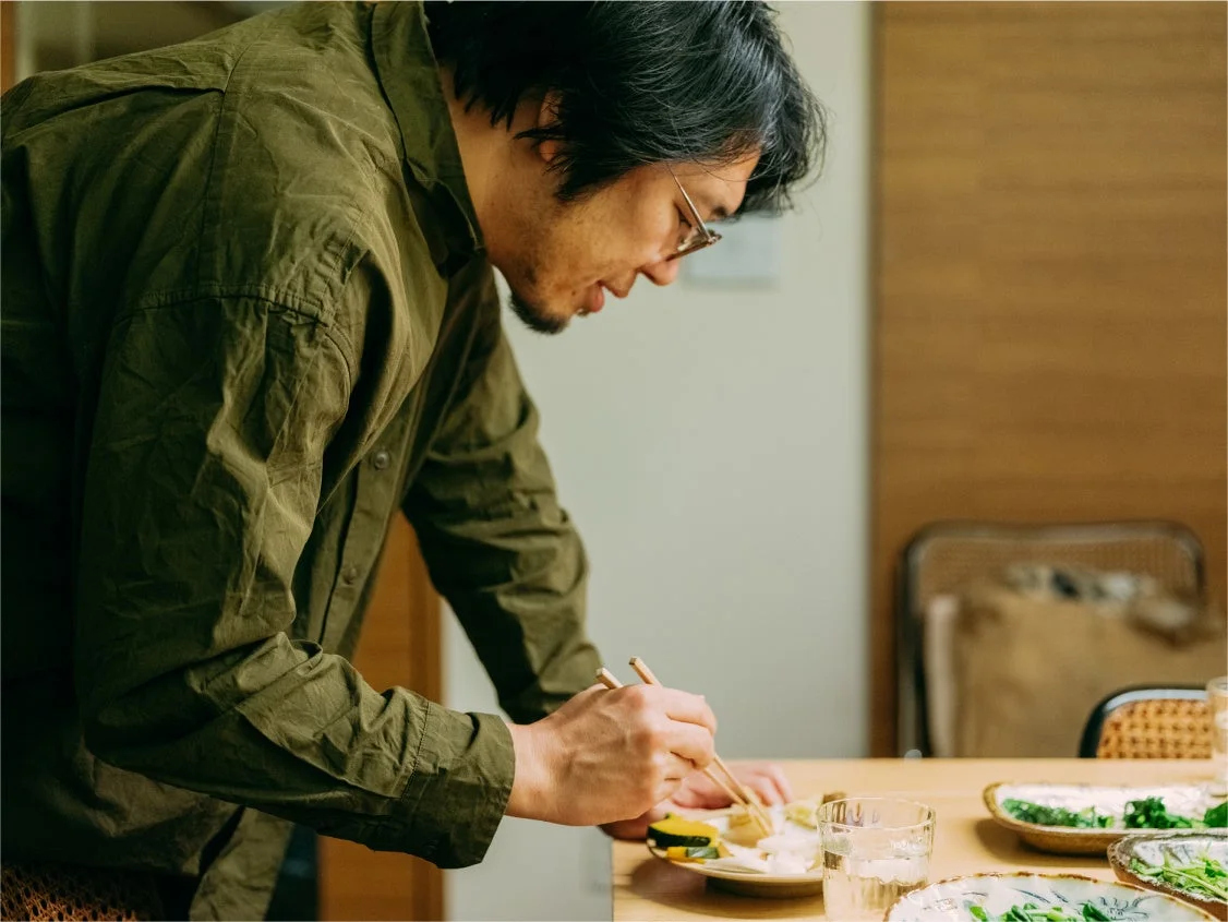 木製のテーブルで箸を使って食事をしている男性