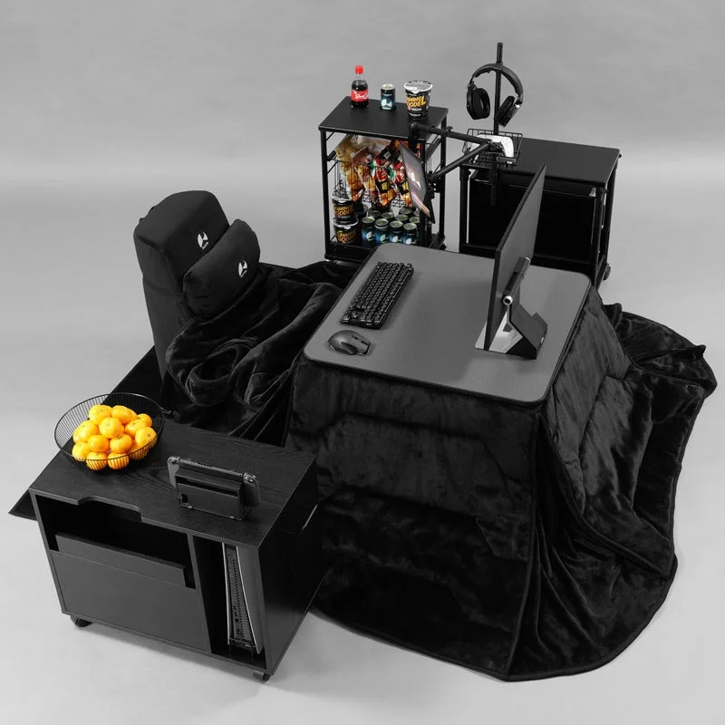 黒を基調としたゲーミングコタツセットアップ。ゲーミングチェア、モニター、キーボード、マウスが配置され、飲み物やスナックも完備された快適なインドア空間です。