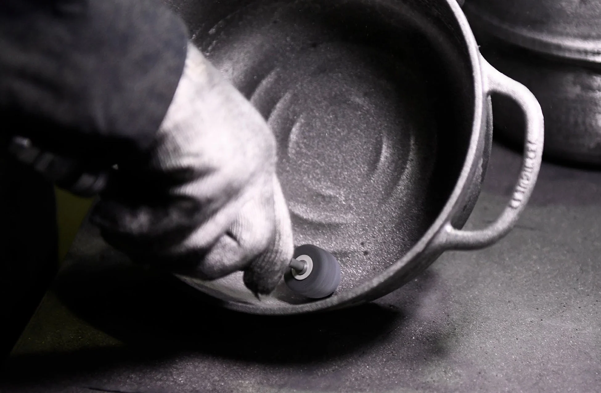 手袋をはめた作業員が鋳物の鍋の内側を研磨