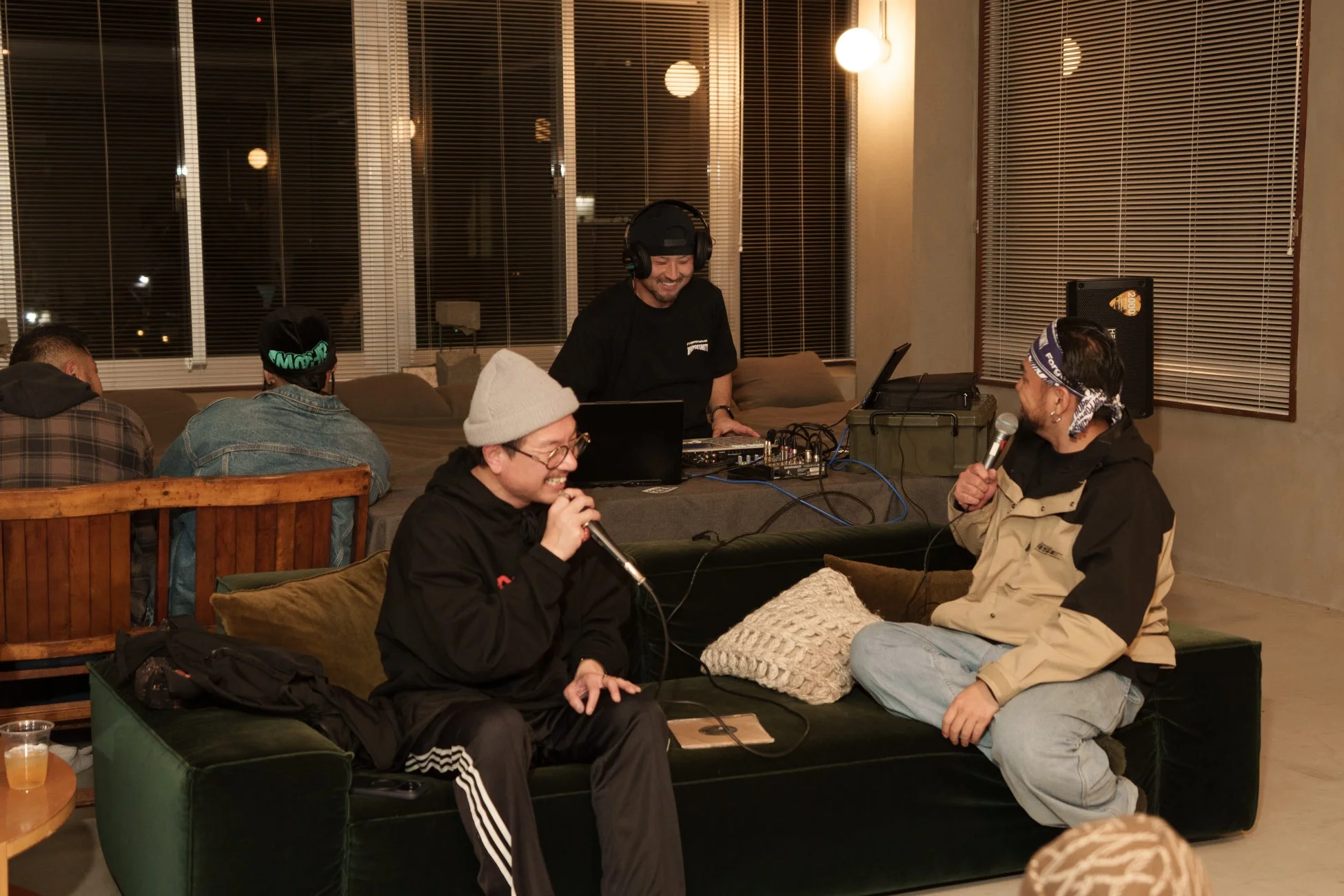 複数の男性が屋内で集まり、DJとトークセッションを楽しんでいる様子