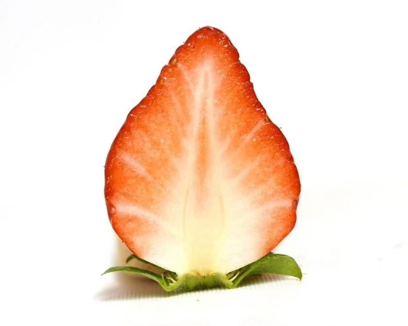 白い背景に、縦に半分にカットされた新鮮なイチゴの断面