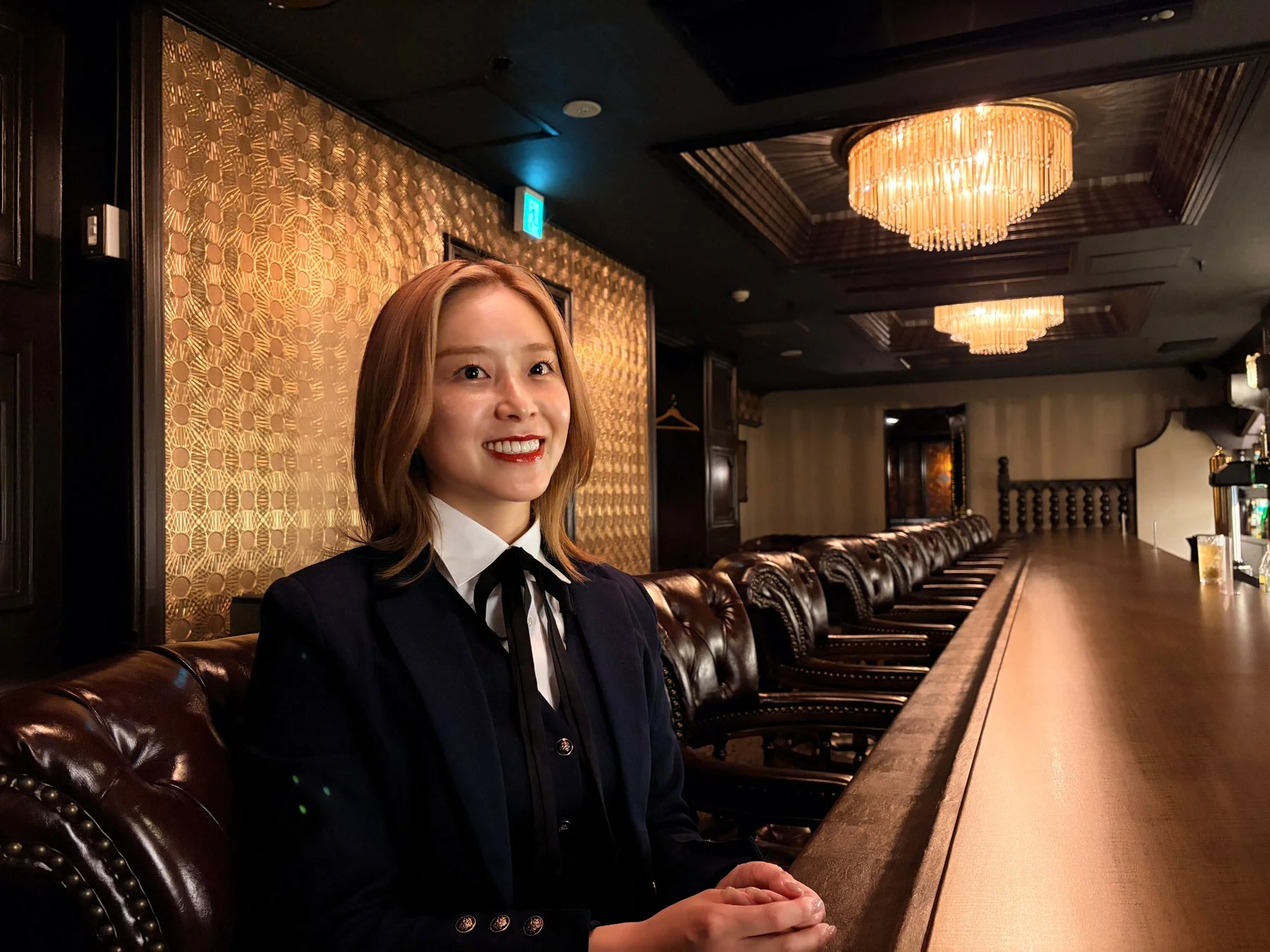 エレガントなバーのカウンターに座り、笑顔を見せる若い女性