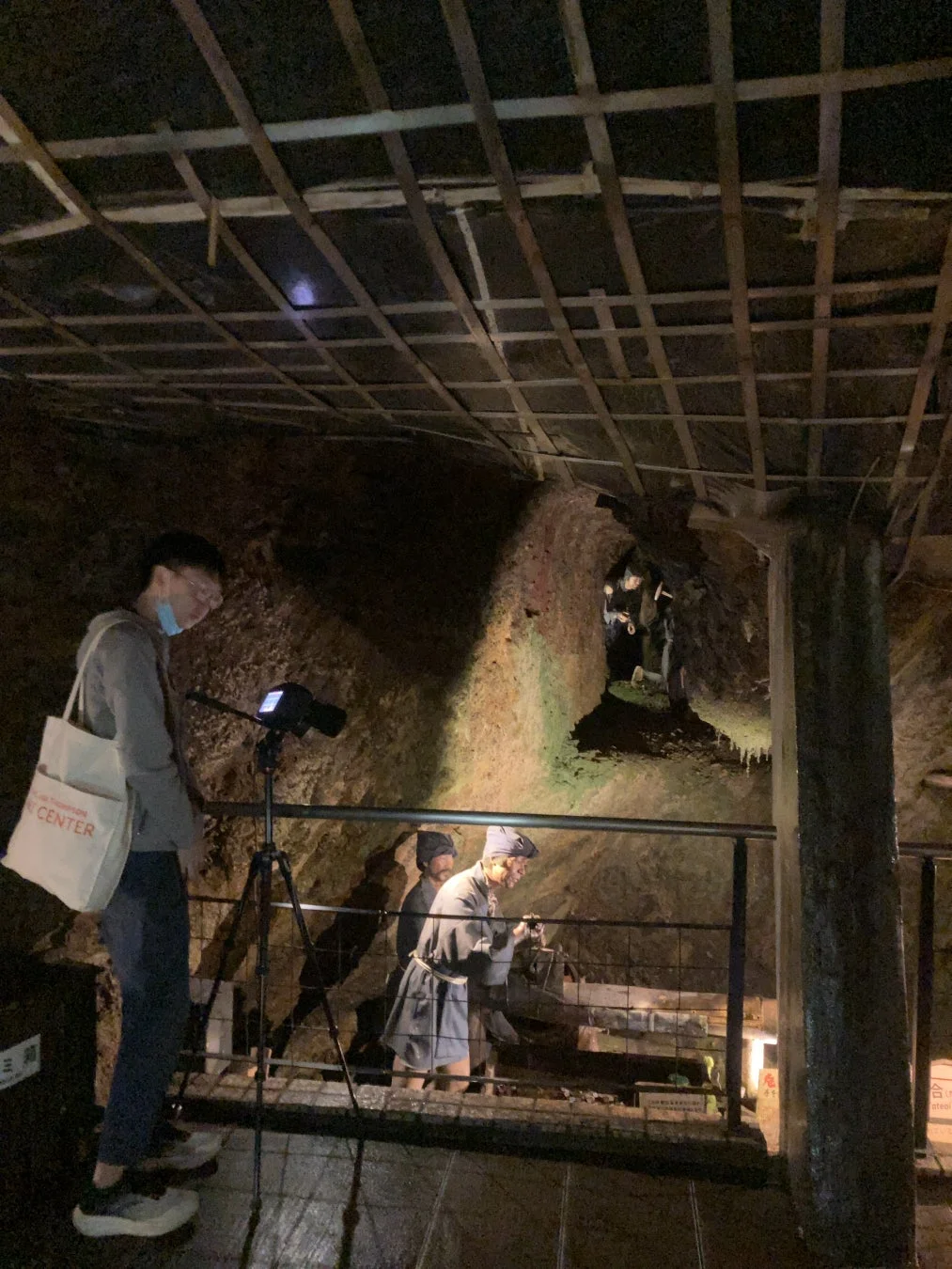 地下坑道内で、マスクを着用した観光客と採掘作業を行う様子の人形が展示