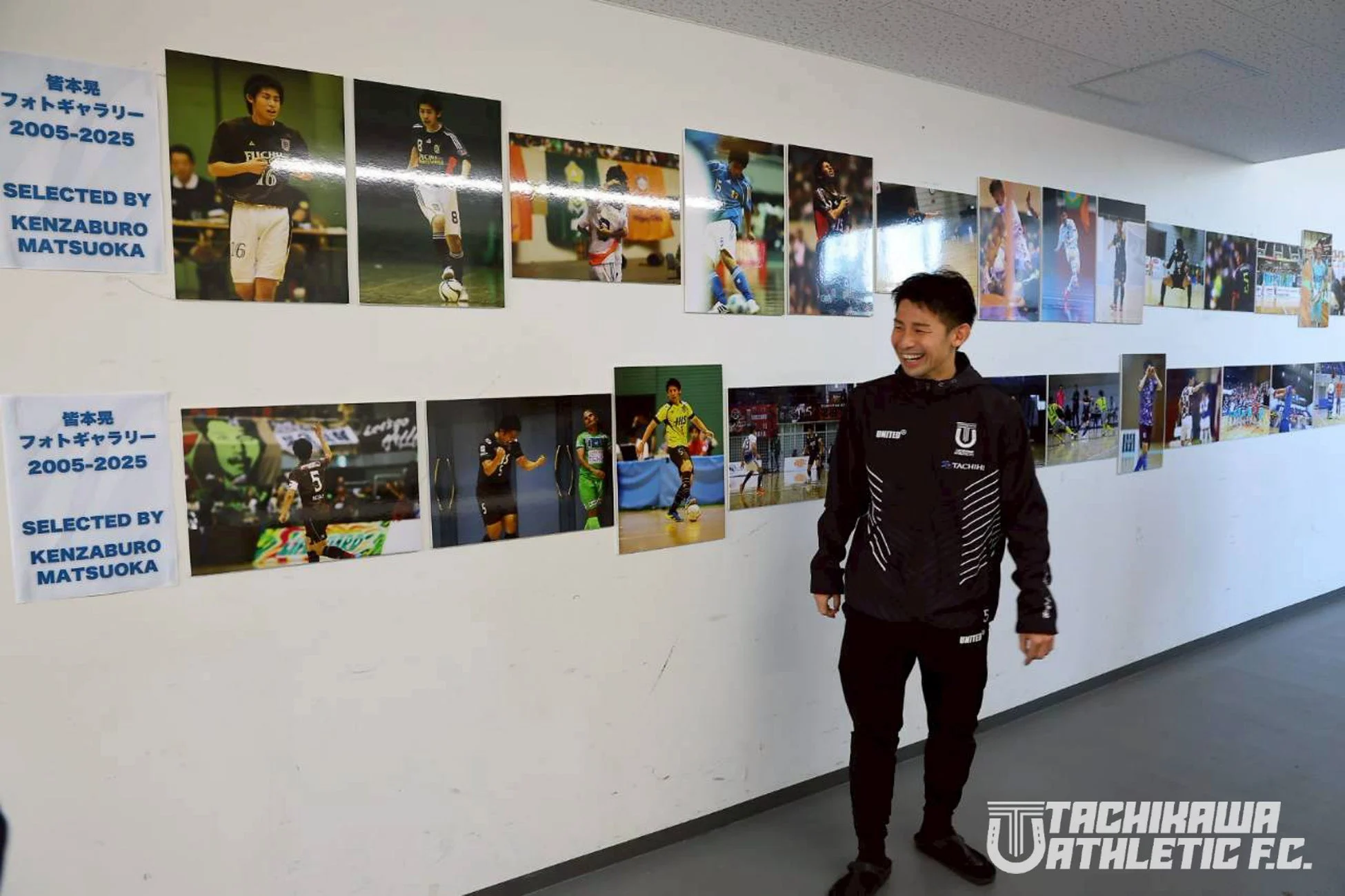 フットサル選手の皆本晃氏のキャリアを振り返る「フォトギャラリー2005-2025」の前で、男性が笑顔で立っている